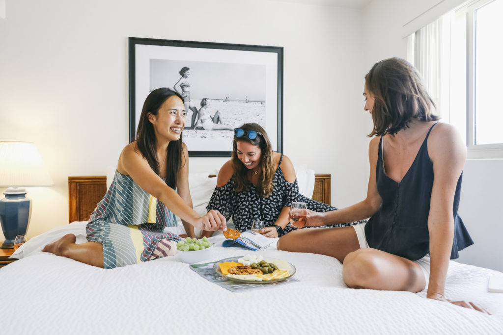 Girls eating charcuterie on the bed.