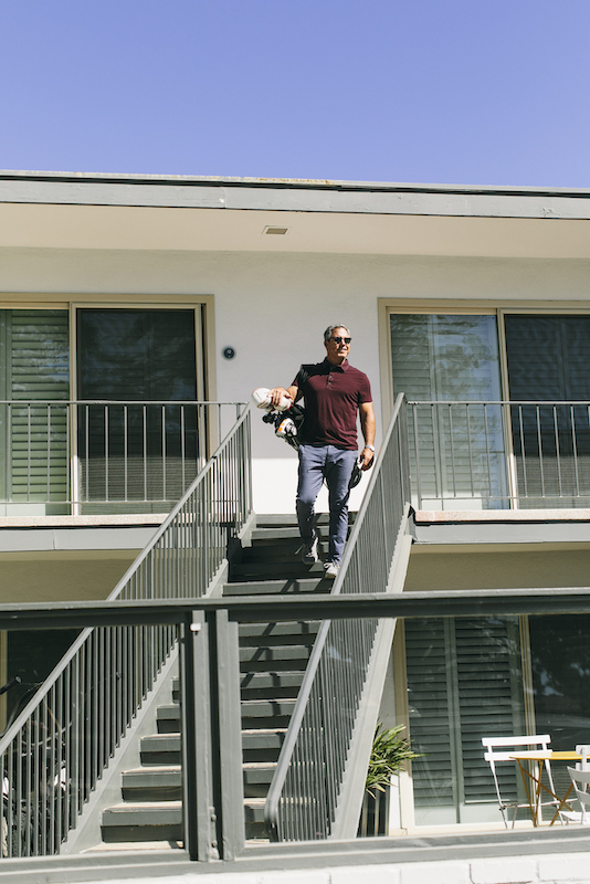 Man leaving hotel room with golf clubs